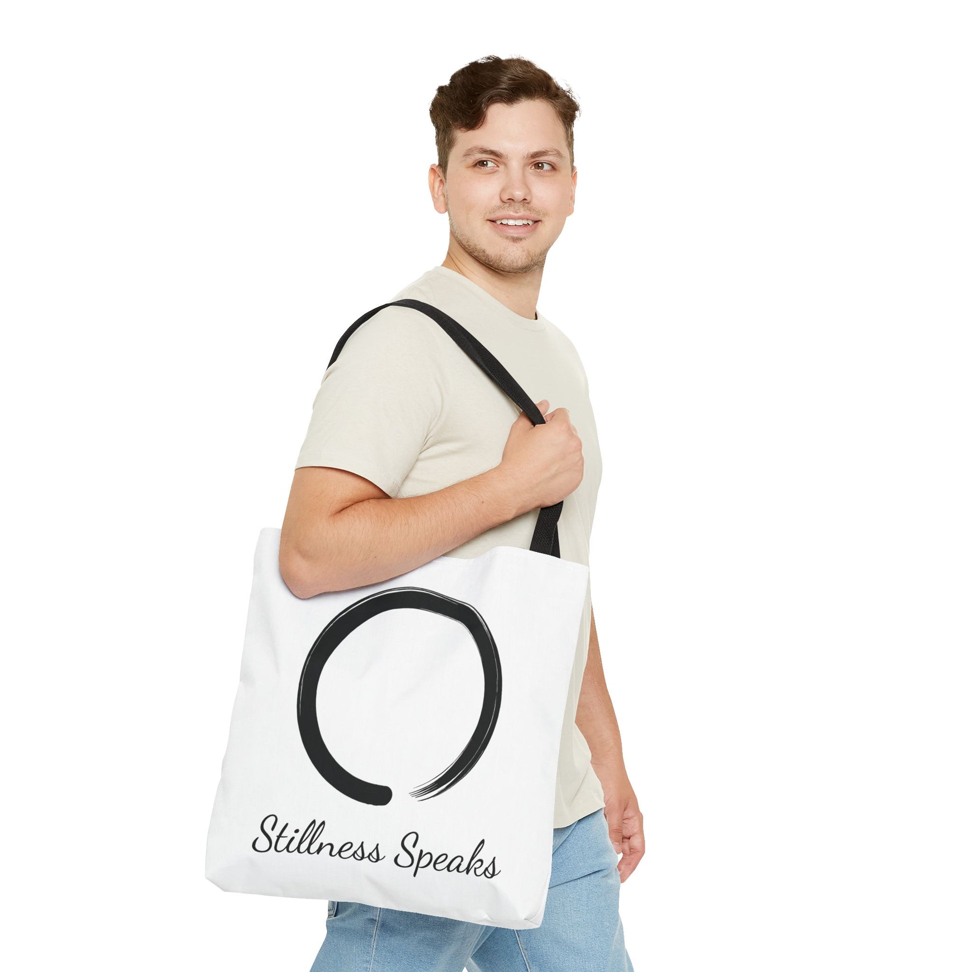 Man holding a tote bag with 'Stillness Speaks' text and symbol on a white background