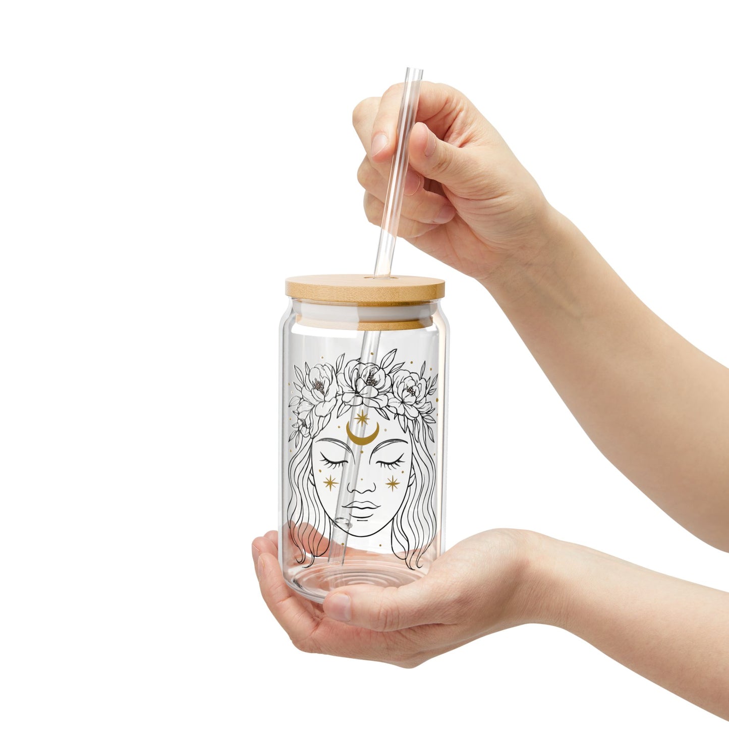 Glass tumbler with bamboo lid and straw held by a hand on a white background