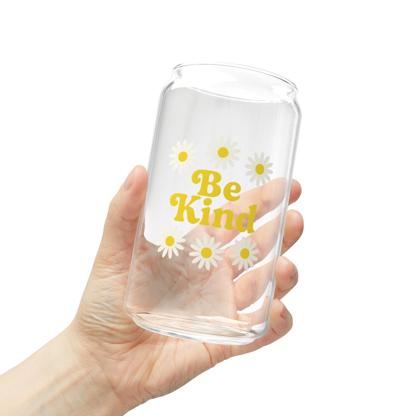 Clear glass tumbler with 'Be Kind' text and daisy flowers held in a hand against a white background