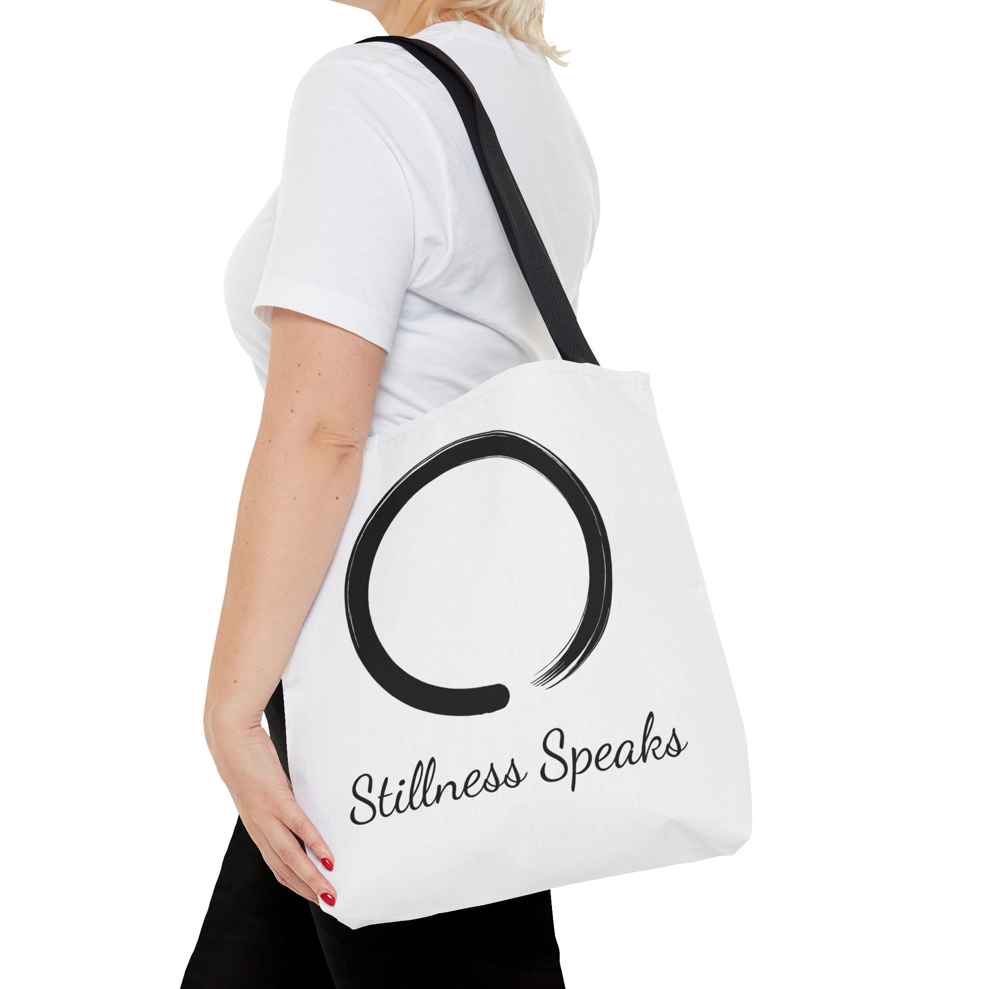 Person holding a white tote bag with 'Stillness Speaks' text and symbol.